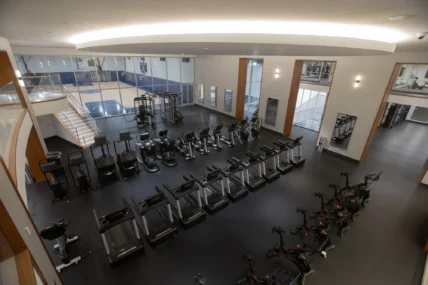 rows of fitness equipment overlook a basketball court