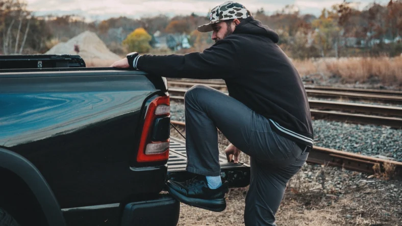 man climbs on a pickup trick wearing Stoke sneakers