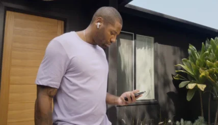 man looks at his phone while wearing AirPods