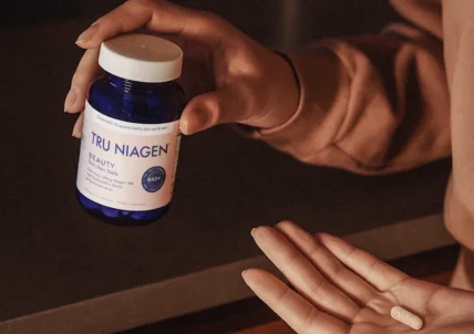 woman holds Tru Niagen Beauty pill