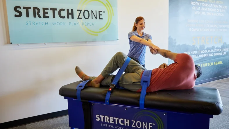 woman stretches a male client at a Stretch Zone